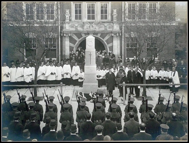 Photo of New Malden War Memorial, soldiers at arms in the foreground, Christ Church choir in the background with Reverend Alvan Birkett on the right
