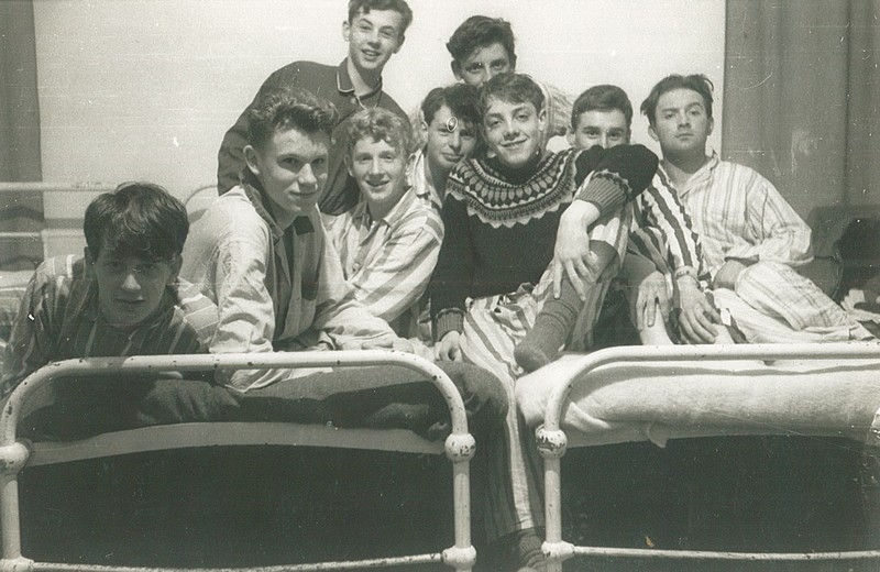 Photo of a group of pyjama-clad boys sat on two adjacent beds taken at a Kings Own House Party