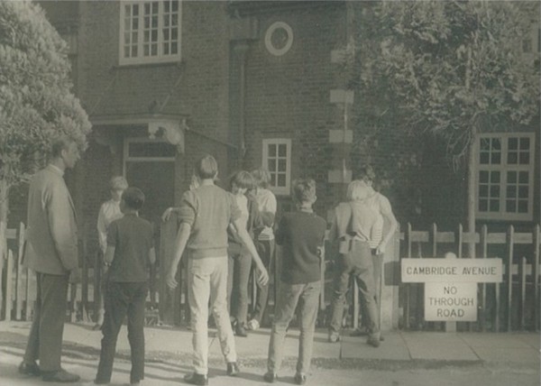 Photo of some Pathfinder boys outside the Parish Halls (the Cambridge Avenue road sign visible) with the curate Bryan Underwood on the left