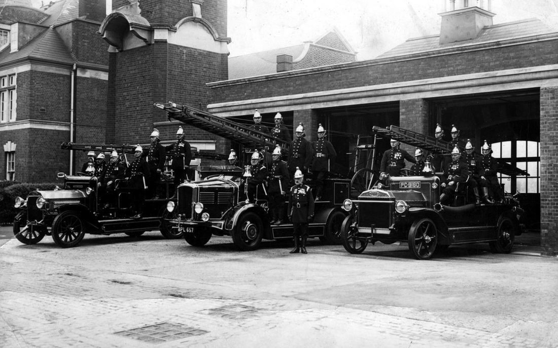 Photo of New Malden fire station c1930 showing three fire engines with ladders and several firemen around each